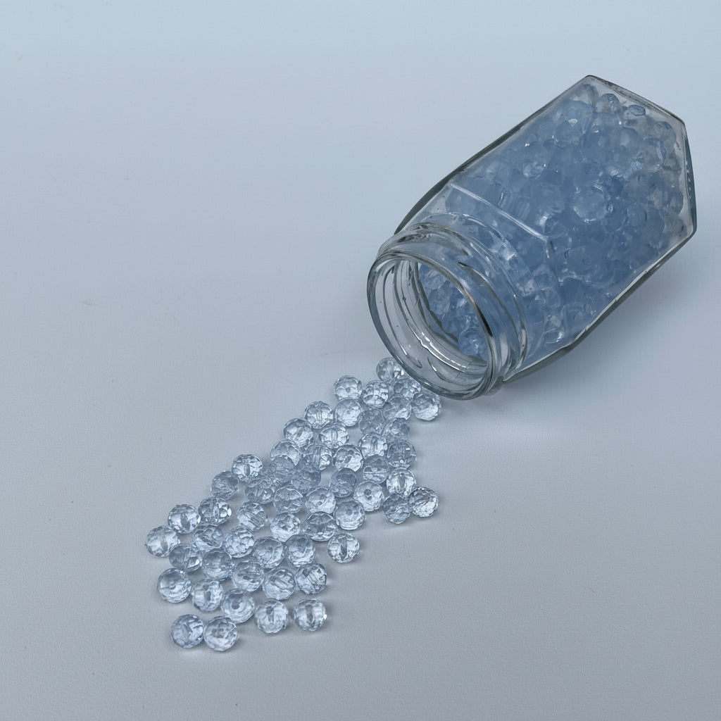 Clear glass jar with spilled clear crystals on a light gray background