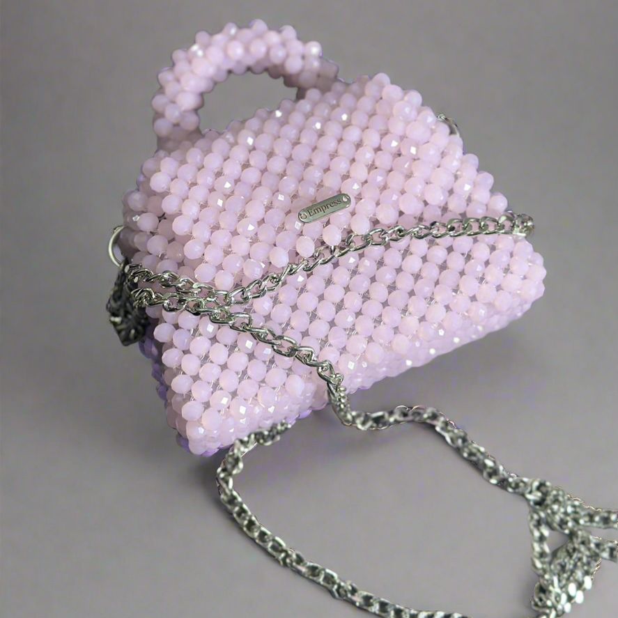 Pink beaded handbag with a chain strap on a gray background