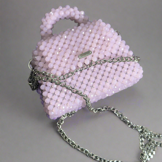 Pink beaded handbag with a chain strap on a gray background