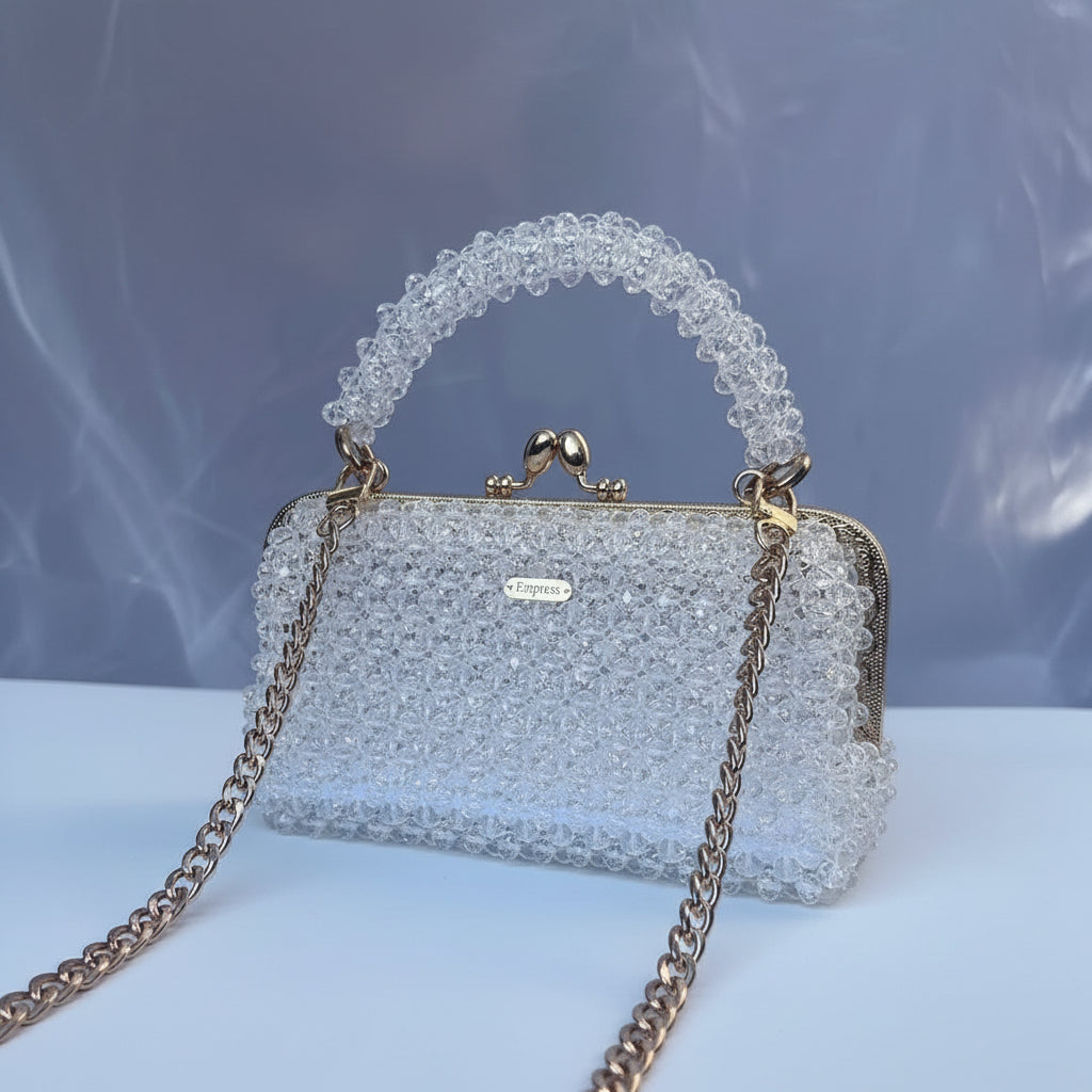 Sparkling handbag with beaded handle on a reflective surface
