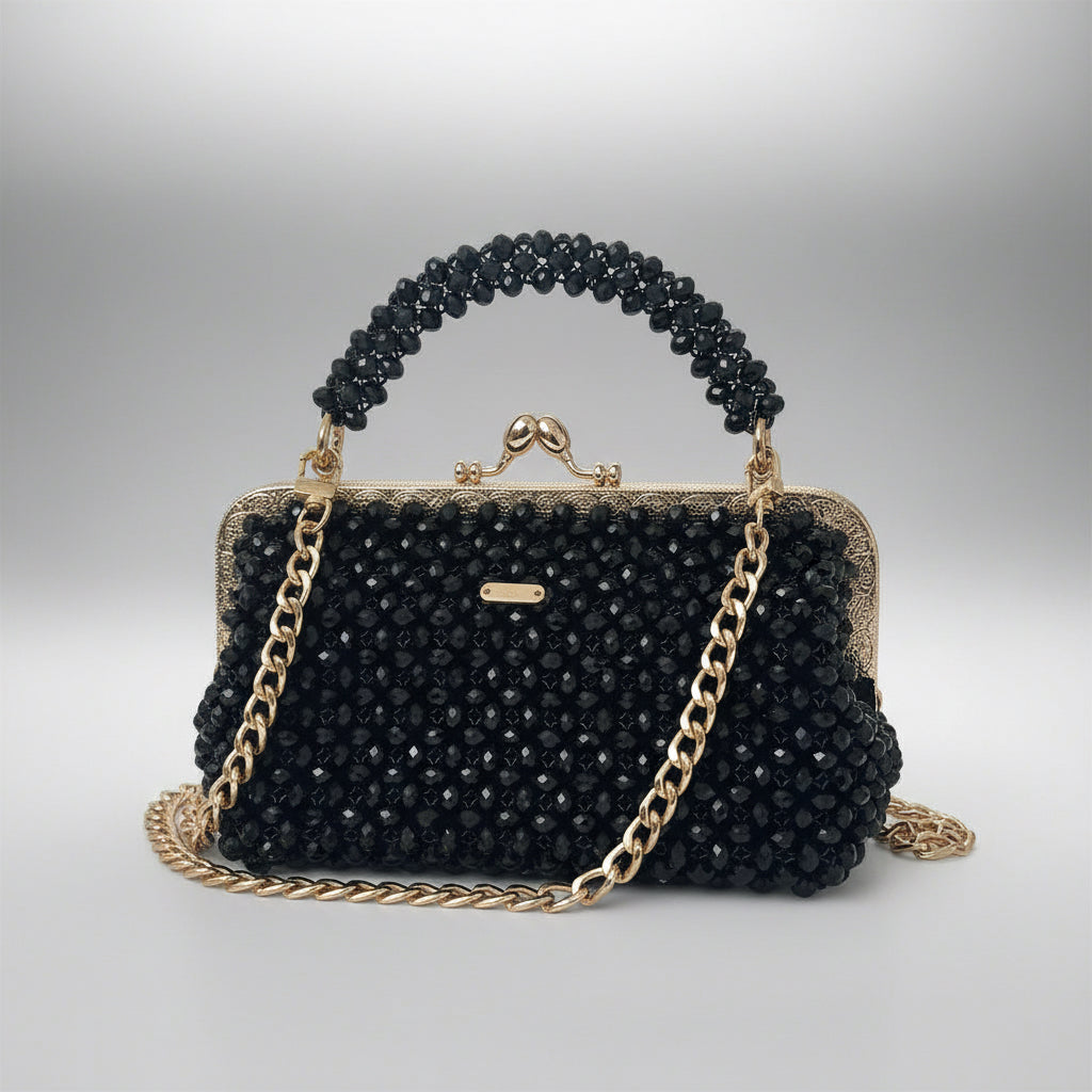 Black beaded handbag with gold chain and handle on a light gray background