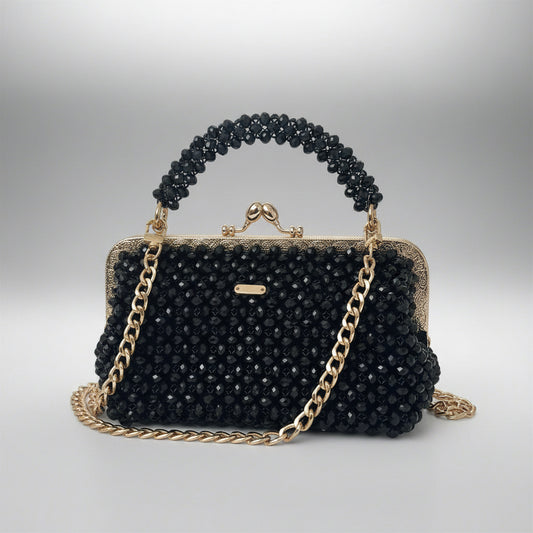 Black beaded handbag with gold chain and handle on a light gray background