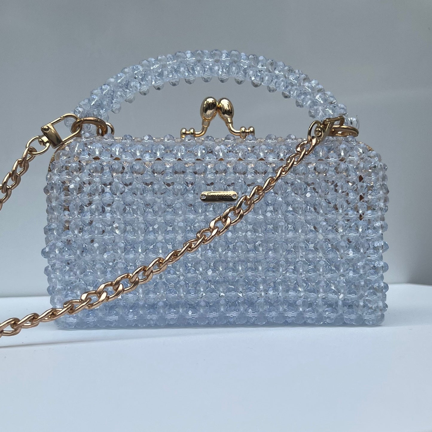 Crystal beaded handbag with gold chain on a white surface