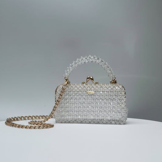 Crystal handbag with gold chain and handle on a light gray background
