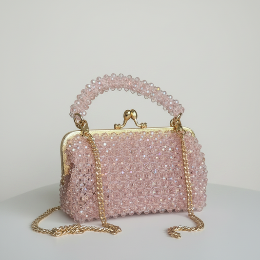 Pink beaded handbag with gold chain on a white surface