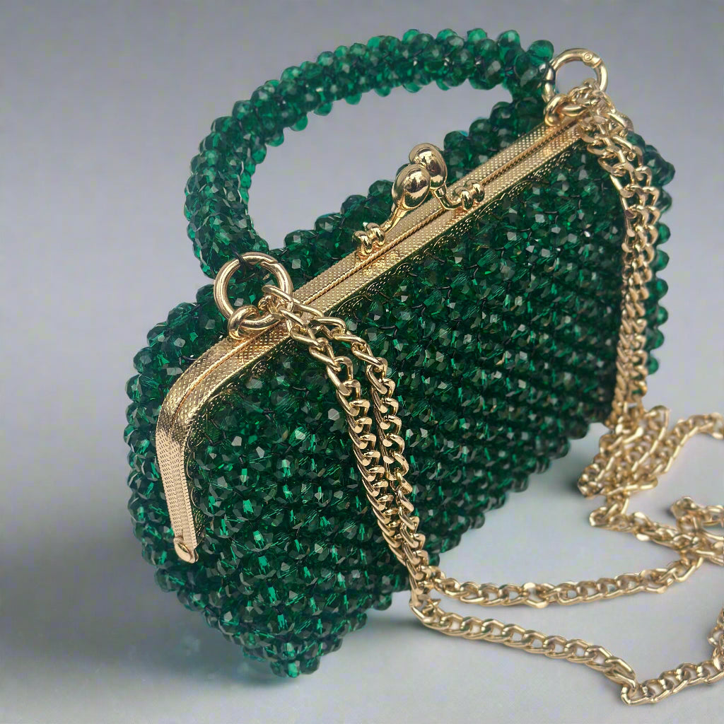 Green beaded handbag with gold chain on a light gray background