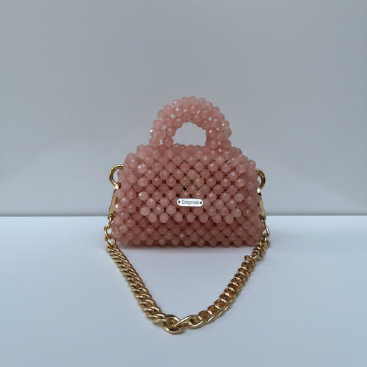 Pink beaded handbag with a gold chain strap on a white background