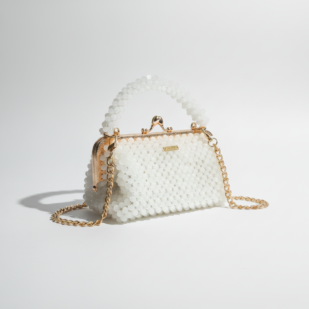 White beaded handbag with gold chain strap on a white surface