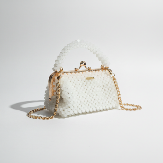 White beaded handbag with gold chain strap on a white surface